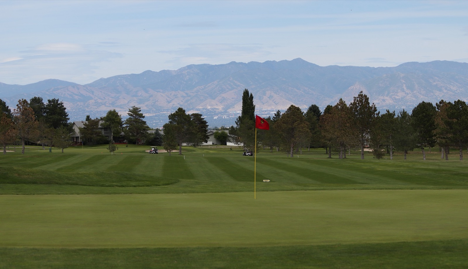 A green and flagstick at Glenmoor Golf Club with mountains beyond